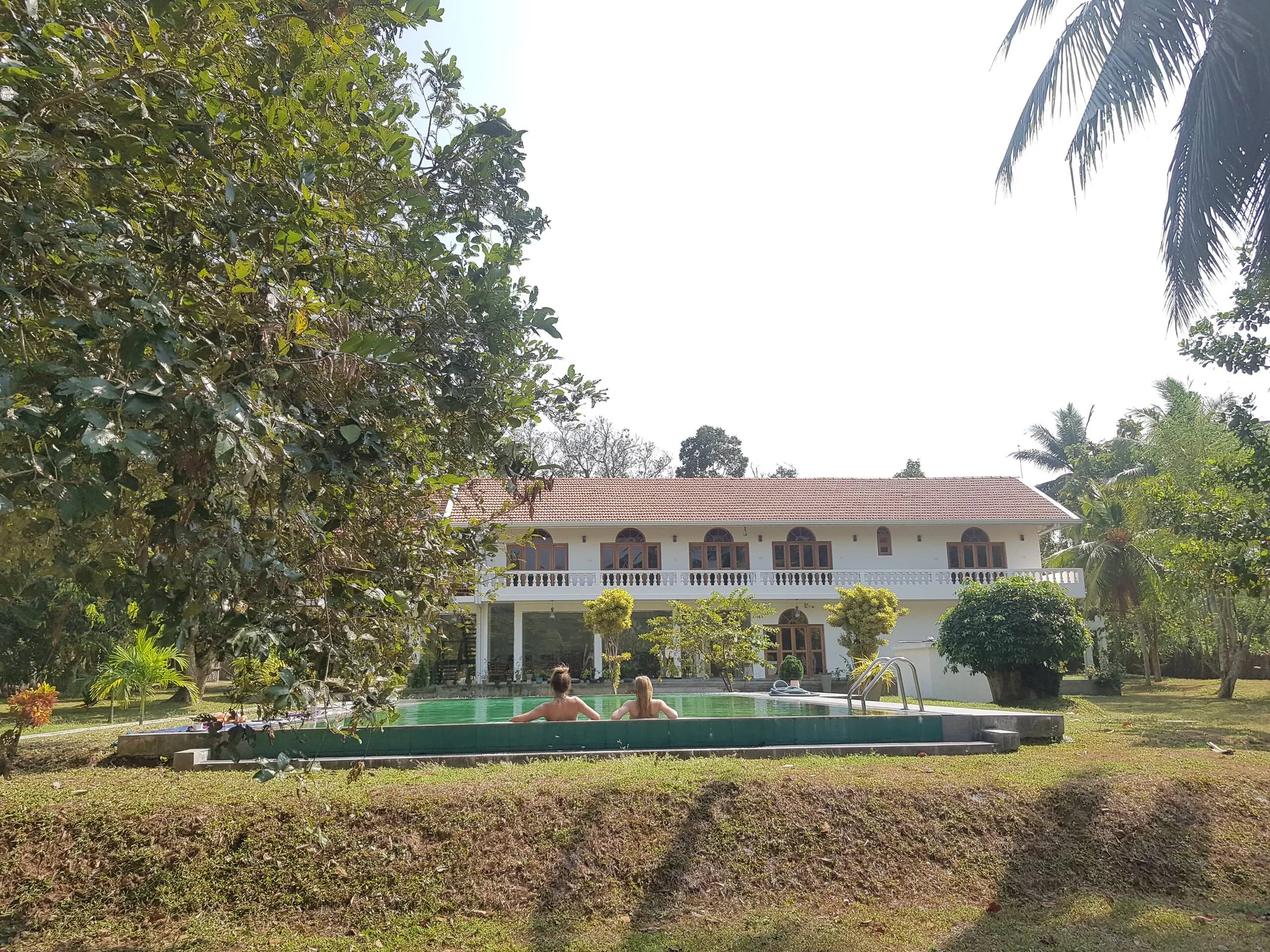 A photograph of the two-storey villa beyond its existing swimming pool